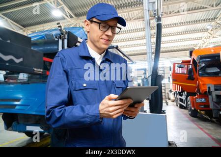 Serviceman with digital tablet on the background of the truck in the garage Stock Photo
