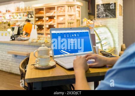 MOSCOW, RUSSIA - SEP 16, 2016: Mans hands keyboarding on laptop in cafe, Apples website on monitor Stock Photo