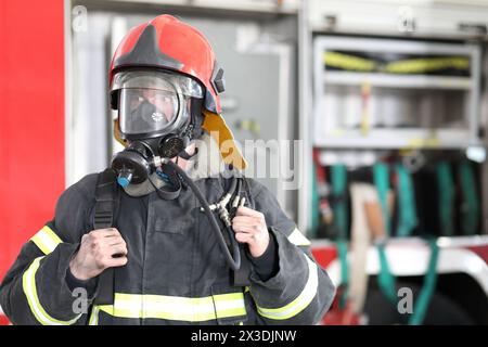 Portrait of fireman wearing fire fighter turnouts and red helmet with breathing apparatus Stock Photo