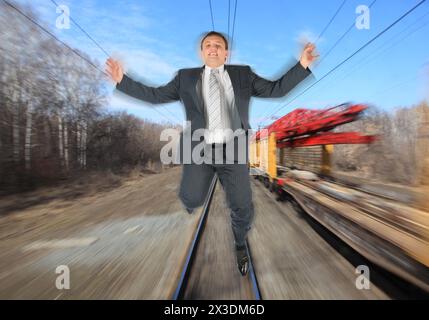 collage with businessman in black suit running away from train on background of railroad tracks, motion blur Stock Photo