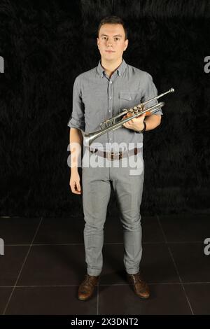 Portrait of a man in a gray suit with a trumpet in his hands in a black room Stock Photo