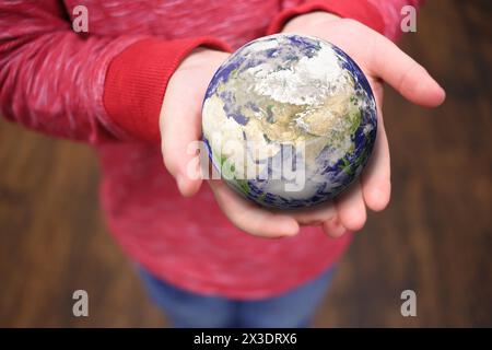 Globe on the hands of a girl in a pink jacket, collage. Elements of this image furnished by NASA Stock Photo