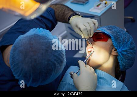 Stomatologist makes anesthetic injection in gum of woman before tooth treatment. Stock Photo