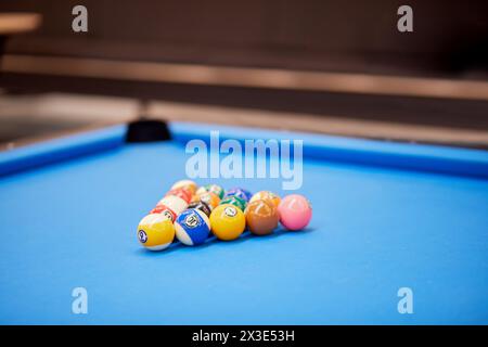 Pool balls set arranged as triangle on blue billiard table. Stock Photo