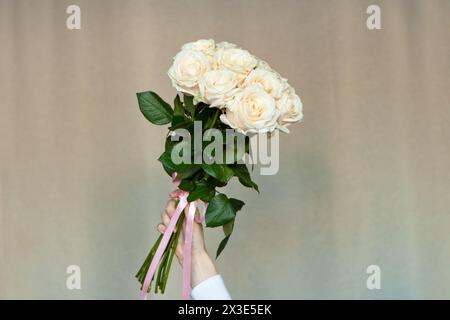white roses in woman hands on brown. girl holding bouquet of fresh roses Stock Photo