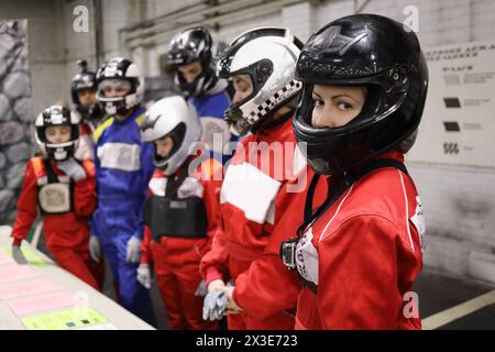 Seven people (three adults and four children) in helmet listen to lesson on instruction before karting, focus on right woman Stock Photo