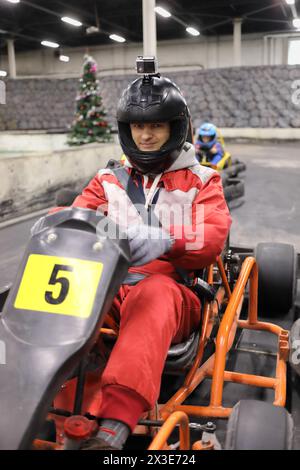 Man in helmet prepares for driving competition of karting, child behind him out of focus Stock Photo