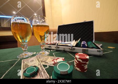 Casino chips in case, cards and dollars, beer in glasses on table Stock Photo