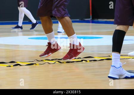 Legs of men in sport shoes and shorts during basketball training in stadium Stock Photo