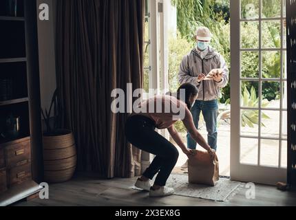 Delivery man, package and woman with mask for logistics, shipping distribution or dispatch service. Covid, female person and courier with tablet for Stock Photo