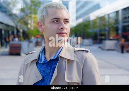 Portrait of young blond short haired latin man standing outdoors looking to side calmly smiling and observing. copy space. business people concept. Stock Photo