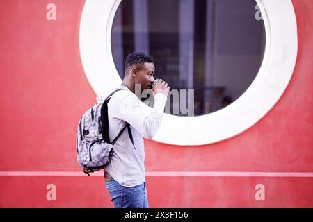 Outdoor, backpack and black man with coffee, walk and morning for university, student and goals for guy. City, fashion and drink of espresso, travel Stock Photo