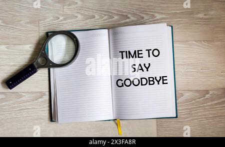 Magnifier and phrase Time to say goodbye written on a notepad, top view Stock Photo