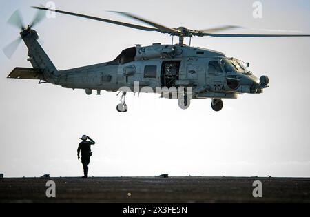 SOUTH CHINA SEA (April 22, 2024) Aviation Structural Mechanic 3rd Class Kory McGarr, from Wimberley, Texas, signals an MH-60R Sea Hawk helicopter assi Stock Photo