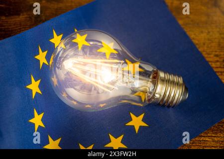 A glowing light bulb lying in the middle of the European Union flag, Concept, Energy prices in EU countries, Changes resulting from energy policy Stock Photo