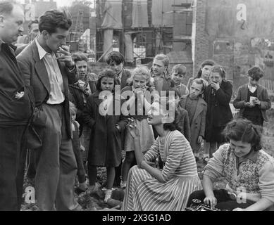 British Actress BARBARA MURRAY chatting with BERNARD FARREL  surrounded by local children during the making of the EALING  comedy PASSPORT TO PIMLICO 1949 filmed on location in a large bombsite in Lambeth Director HENRY CORNELIUS Screenplay T.E.B. CLARKE Music GEORGES AURIC Ealing Studios Stock Photo