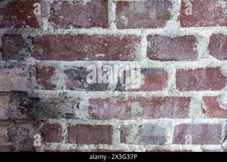Gray structural stone wall of the ancient building consists of old dark brown bricks. Natural background. Stock Photo