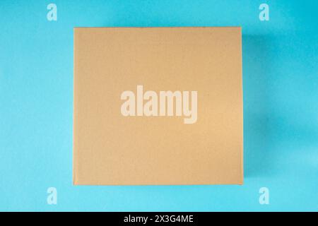 Little cardboard box on blue background. Mockup for design. Stock Photo