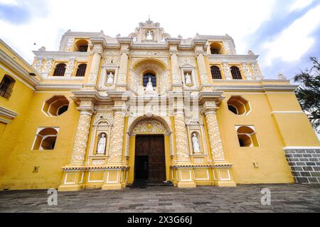 Exterior façade of the Church and Convent of La Merced, an ornate Catholic church built in the Churrigueresque style in 1749 in Antigua, Guatemala. The bright yellow ornate building features relief details in arabesque patterns called Ataurique stucco. Stock Photo