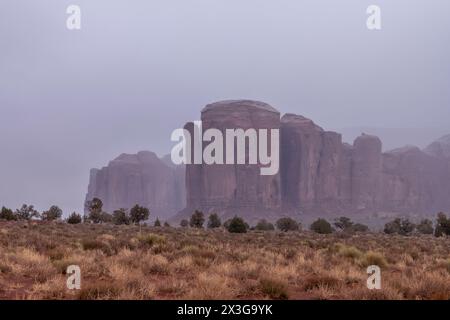 Many areas within Monument Valley host smaller mountainous formations. Shown here is a formation during a rainy day with low clouds lining rocky struc Stock Photo