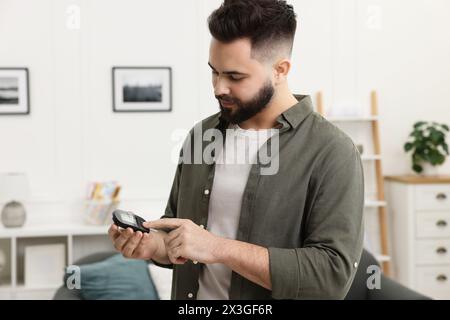 Diabetes test. Man using glucometer at home Stock Photo