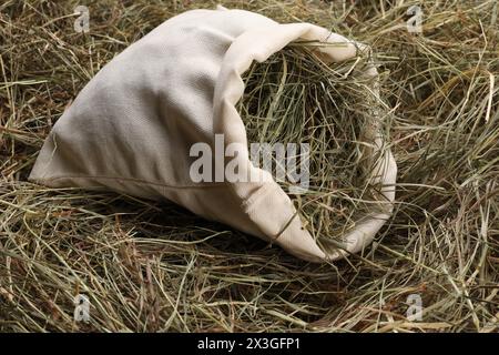 Dried hay in burlap sack on table, closeup Stock Photo