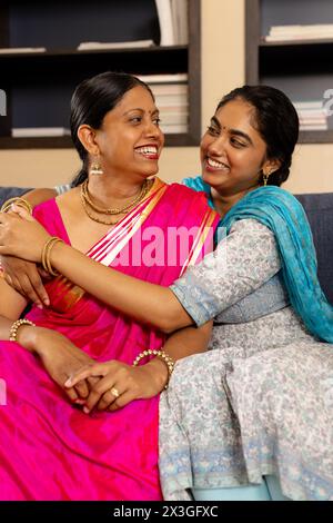 Indian mother and teenage daughter, sitting close at home, sharing happy moment Stock Photo