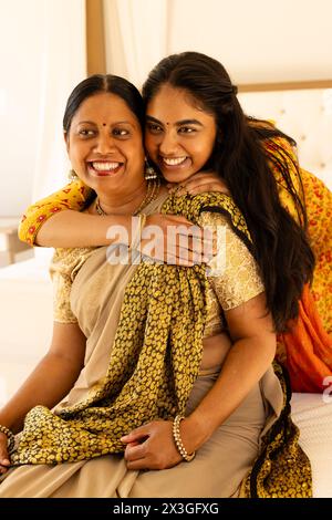 Indian mother, daughter in sarees embrace warmly at home Stock Photo