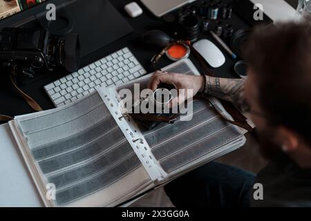 Photographer reviewing film negatives at modern workspace Stock Photo