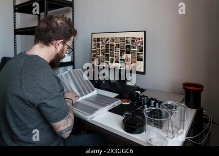 Photographer reviewing film negatives at a modern workstation Stock Photo