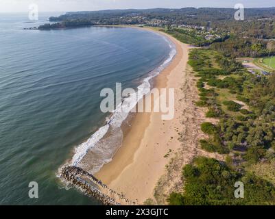 Aerial view of a breakwater at the end of a long sandy beach with gentle waves rolling in at Batemans Bay in New South Wales, Australia. Stock Photo