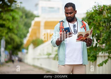 Young tourist with backpack looking at smartphone screen while using navigation application or local map during excursion Stock Photo
