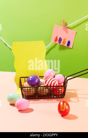 A black basket containing a lot of Easter eggs painted with stripes, flowers and polka dots. Several notes with copy space are hanging on a string. Co Stock Photo