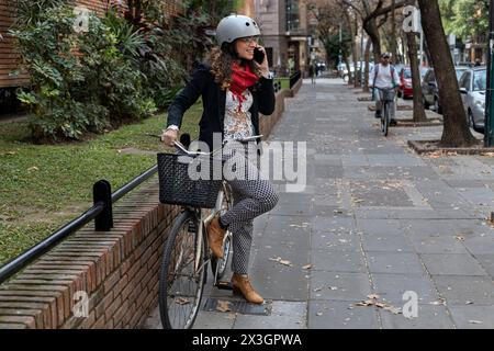Young Latin American businesswoman standing next to her vintage bicycle talking on cell phone Stock Photo