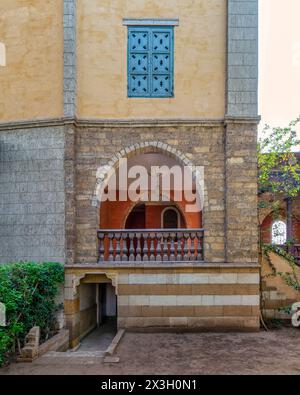 A serene view of a rustic style building featuring an arched wooden balcony, and detailed window grills Stock Photo