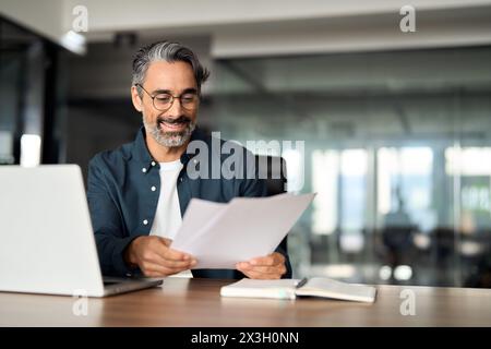 Happy mature professional business man checking documents working in office. Stock Photo