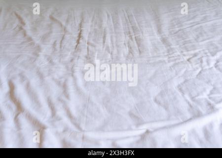 Crumpled or wrinkled white bedding sheet background texture was taken with soft natural light used for clothing background texture. Stock Photo