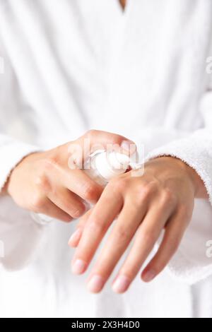 A young Caucasian woman applying lotion to her hands at home Stock Photo