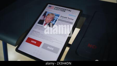 ZAPORIZHYA, UKRAINE -MARCH 15, 2024: Voting booth with tablet computer. Information about Donald Trump and buttons displayed on tablet screen. Modern digital technology for voting. Presidential Elections in the United States of America. Stock Photo