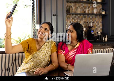 Indian mother and teenage daughter, taking selfie at home by laptop Stock Photo