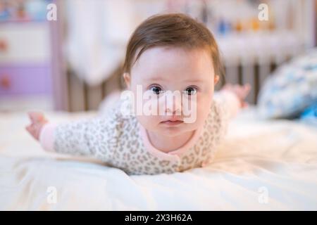 A happy baby girl in white bedding at home Stock Photo