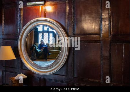 A mystery woman in a round mirror in an old, oak-panelled room Stock Photo