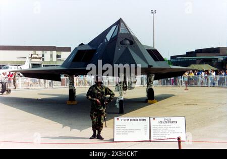 Lockheed F-117A Nighthawk 'Stealth Fighter' 85-0830 on display with armed guard and Gulf War statistics at the Mildenhall Air Fete 1992. This was the Lockheed stealth fighter's first public UK appearance following worldwide media coverage of the fighter-bomber's night time capabilities during Operation Desert Storm of the Gulf War. The USAF used the F-117 to bomb important targets such as bunkers and aircraft shelters, as listed on the display board. Female armed guard. From 37th Tactical Fighter Wing USAF this aircraft flew a number of missions during the campaign Stock Photo