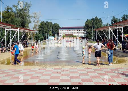 children and adults in city fountain on hot sunny day. freshness in heat. children and adults refreshing themselves in city fountain in urban park in Stock Photo