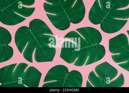 Creative nature pattern composition made with green tropical leaves on light pink background. Minimal summer jungle or forest pattern background image Stock Photo