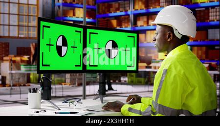 Engineer Using PC Monitor With Green Screen At Warehouse Stock Photo