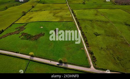 Vibrant green fields curve through the landscape. Sky is clear with ...