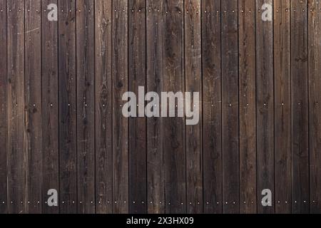 A closeup shot of a brown wooden fence with holes in the planks. Stock Photo