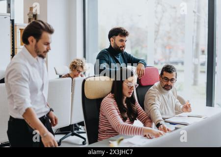 Different aged coworkers collaborate happily in a modern office lobby, using technology and teamwork to achieve successful results. Stock Photo