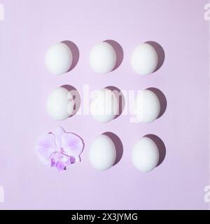 Creative layout made of eggs and orchid flower on pastel purple background. Flat lay. Easter concept. Stock Photo
